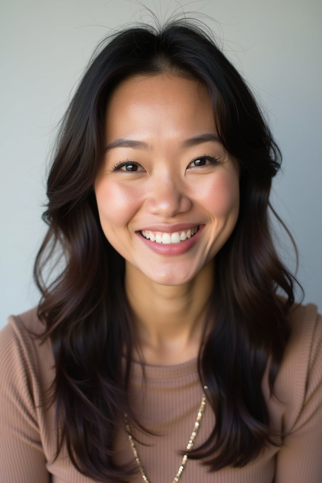 A professional comedian headshot taken in a well-lit studio with a clean, neutral backdrop. The woman is dressed in a stylish yet playful fitted top with natural makeup and a confident smile , ensuring a polished yet approachable look. The lighting is soft and even, highlighting the woman’s expressive face, charisma, and subtle comedic charm. The focus is sharp, capturing a warm and inviting expression, creating the perfect headshot for stand-up comedians, improv actors, and comedic performers.