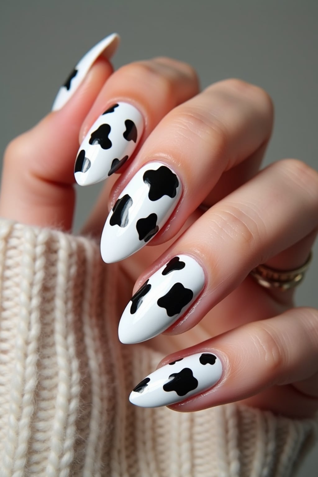 cow print nails on glossy white base, bold and playful aesthetic, beauty studio lighting, fashion-forward hand styling