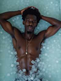 man lying in a bath of ice cubes