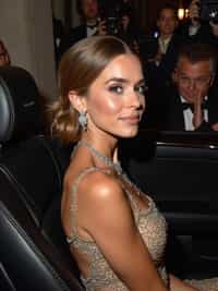 woman departing the Met Gala in a luxury vehicle, wearing a glamorous after-party look with statement jewelry , paparazzi and fans outside the Metropolitan Museum with event lighting visible