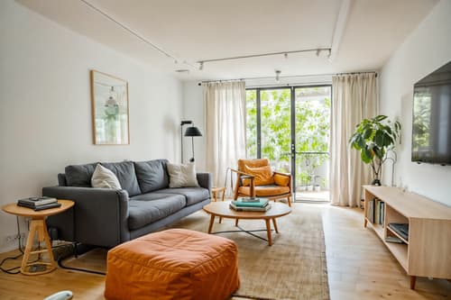 Photo from Pinterest of Airbnb-style interior designed (living room interior) With sofa and televisions and chairs and bookshelves and electric lamps and furniture and occasional tables and plant. . With Scandinavian style and Open and Natural Lighting and Simple, Clean Lines and Simplistic Furniture and Practicality and Functionality and Simple Color Palette and Neutral Walls and Textures and Natural Materials and Elements and Scandinavian style. . Cinematic photo, highly detailed, cinematic lighting, ultra-detailed, ultrarealistic, photorealism, 8k. Trending on Pinterest. Airbnb interior design style